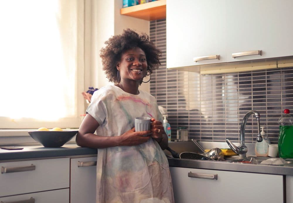 A woman in her kitchen holding a cup